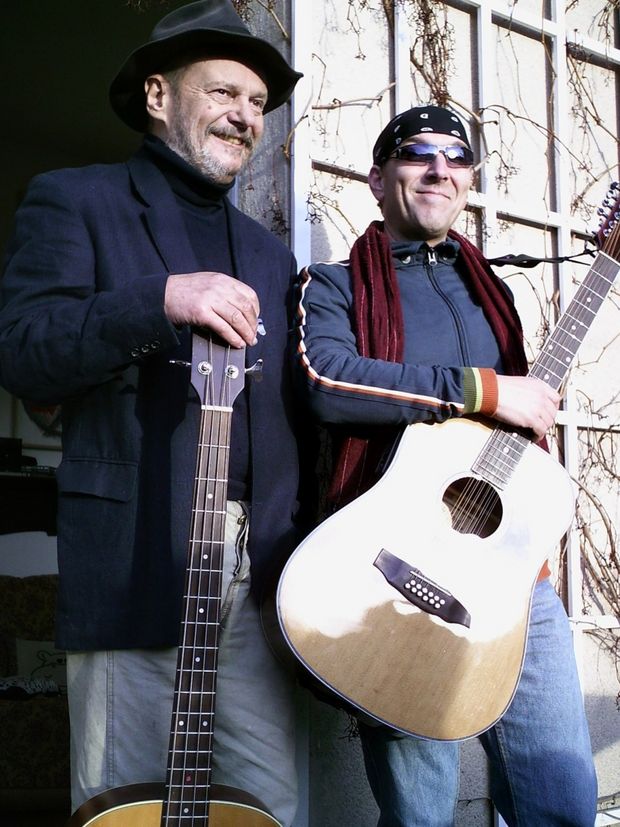 Zwei Gitarristen vor einem Haus